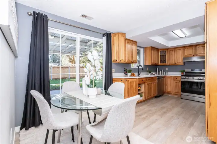 This angle shows how the kitchen flows directly into the dining nook, creating a casual eat-in setup that works well for daily meals. The glass table staging demonstrates there’s comfortable room for seating without crowding the space. The sliding door nearby enhances indoor-outdoor connectivity and keeps the dining area light and airy.