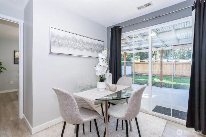 Here you see the dining space’s connection to the backyard more clearly. Large glass sliders bring in natural light and offer easy access to outdoor entertaining or play space. Curtains frame the doors nicely, softening the look while maintaining privacy when needed. It’s a bright, practical extension of the kitchen.