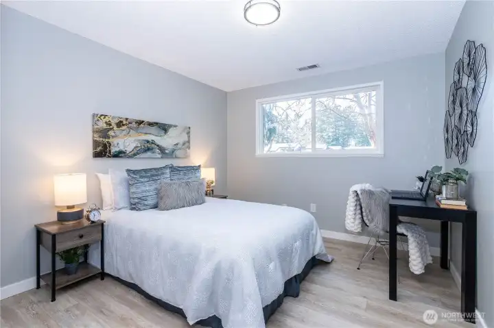 This bedroom offers a comfortable footprint with enough space for a full bed setup plus additional furnishings. The window placement allows natural light to filter in while maintaining privacy, giving the room a bright but relaxed atmosphere. Neutral paint tones and updated flooring make the space move-in ready and adaptable to a variety of uses — whether as a guest room, home office or traditional bedroom. The staging demonstrates flexibility, with room for side tables, a desk or reading nook without crowding the layout. Clean lines and modern finishes continue the home’s cohesive aesthetic, making this a functional and inviting secondary bedroom suited for everyday living or overnight guests.