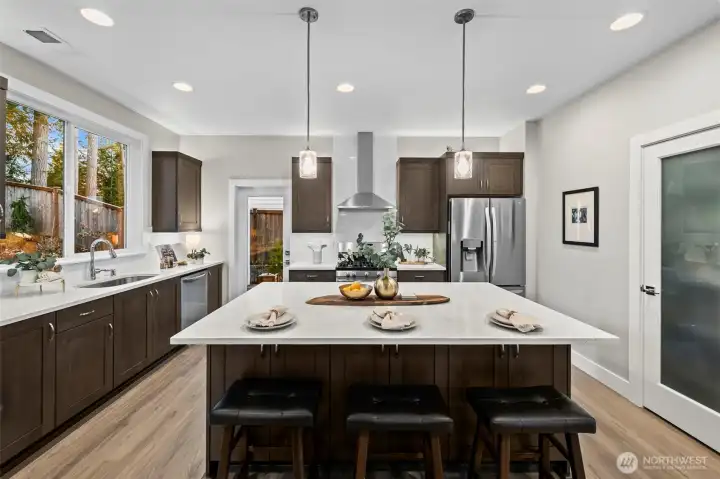 The oversized kitchen island is upgraded with double backed wood cabinets as well as the extended quartz for bar seating providing plenty of additional storage.