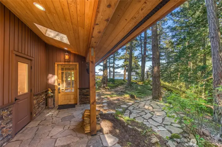 Covered entrance on the south side of the home with pathways and trails through the forest and along the shoreline. Arriving home, the view, serenity and fresh air will call you to explore and recharge in nature.