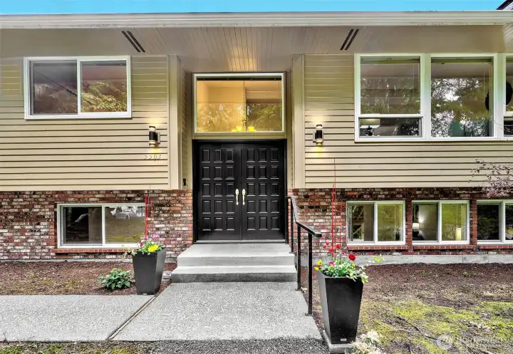 Showing the covered porch, large windows and double door entrance.