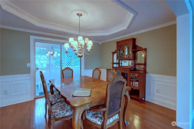 Another view of the formal dining room with hardwood floors, wainscoting, coffered ceiling and beautiful chandelier