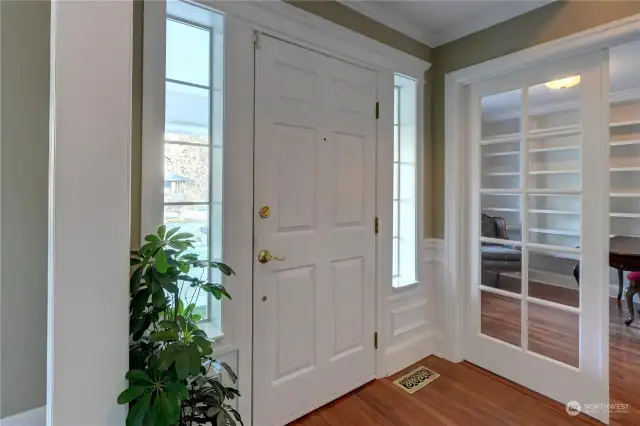 In the entry hall with hardwood floors, and French Doors that lead to the den with custom shelves and millwork