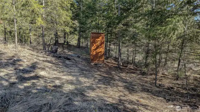 There is an outhouse North of cabin.