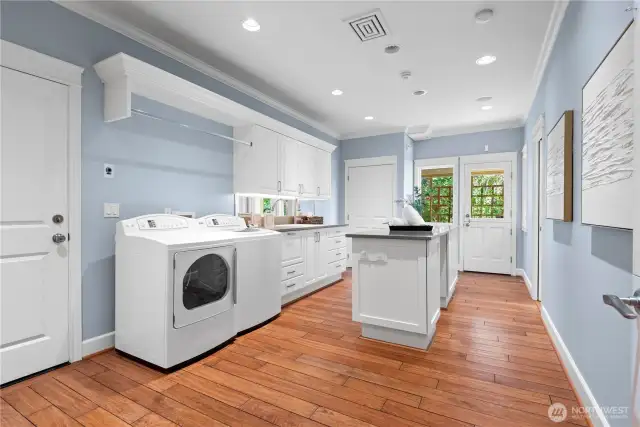 This spacious and beautifully designed laundry room offers a central island for folding and organization, paired with a thoughtfully placed ¾ bath—combining practicality with refined comfort.