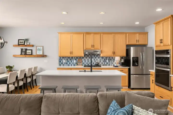 Updated kitchen includes quartz counters, stainless appliances, counter seating and warm wood cabinets.