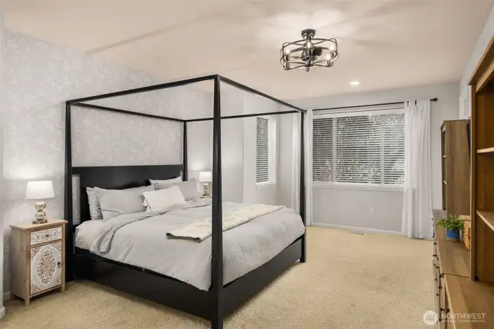 A main floor primary suite! This is a king size bed and there is plenty of room near the windows for a chair or two.