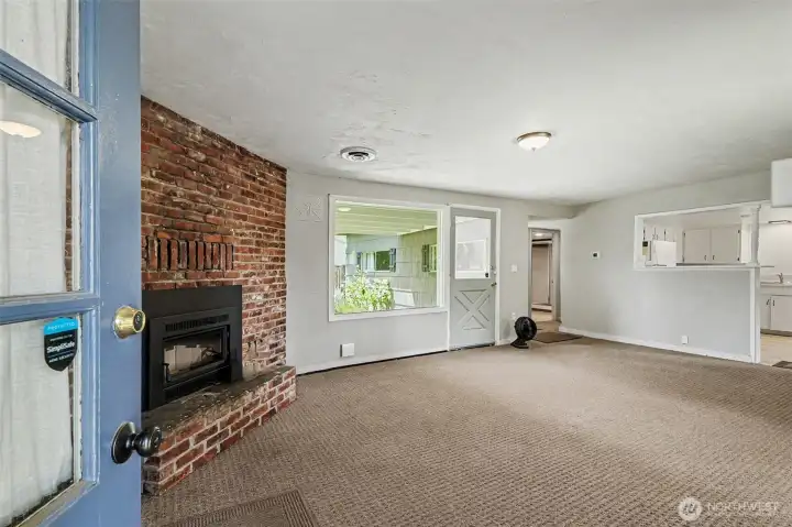 The home opens to a warm and inviting living room featuring a classic brick fireplace, creating a cozy focal point for everyday living