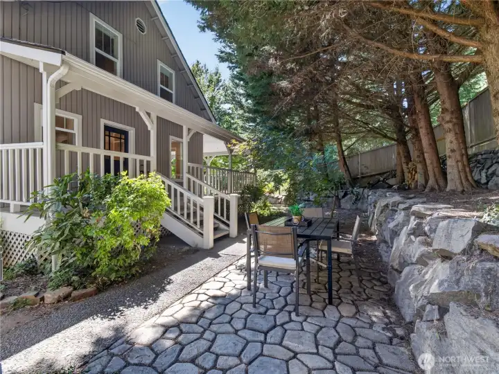 A charming stone patio creates the perfect setting for morning coffee, al fresco dining, or unwinding beneath the canopy of mature evergreens.