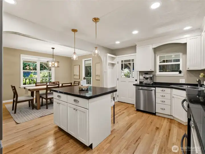 Crisp white cabinetry, gleaming stone countertops, and warm hardwood floors create a bright, welcoming space, while the oversized island invites everything from casual breakfasts to gathering with friends over appetizers and conversation.