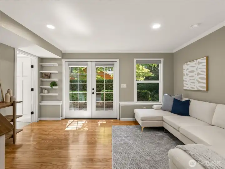 French doors open to the outdoor patio, creating a seamless indoor-outdoor connection, while large windows fill the room with natural light.