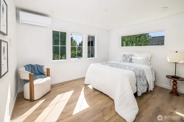 Top floor primary suite with green views, natural light and thoughtful design elements including nightstand light switches and TV mount station midway up wall for ease of mounting without wire and cable showing.