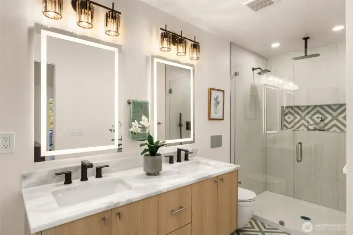 The primary suite features an en-suite bath, with dual vanity, tasteful full surround tile, and rainfall shower head for a true spa-like experience
