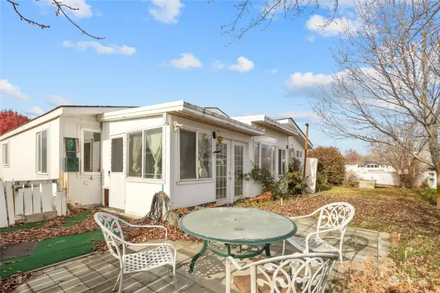 Rear of home- showing the enclosed back porch addition! Cute outdoor dining patio & BBQ deck.