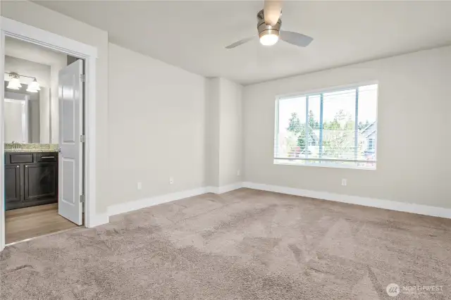 Peaceful primary suite featuring a walk-in closet and private bath with dual sink vanity and tile shower.