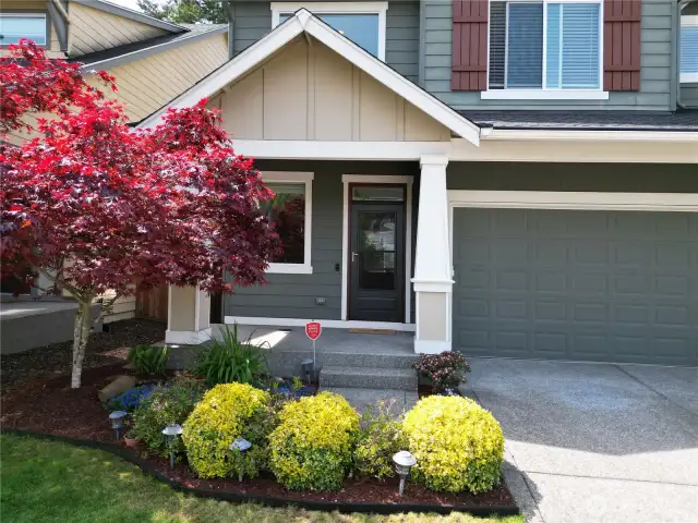 The front entry is highlighted by graceful columns and lush greenery creating a warm, inviting entrance to the home.
