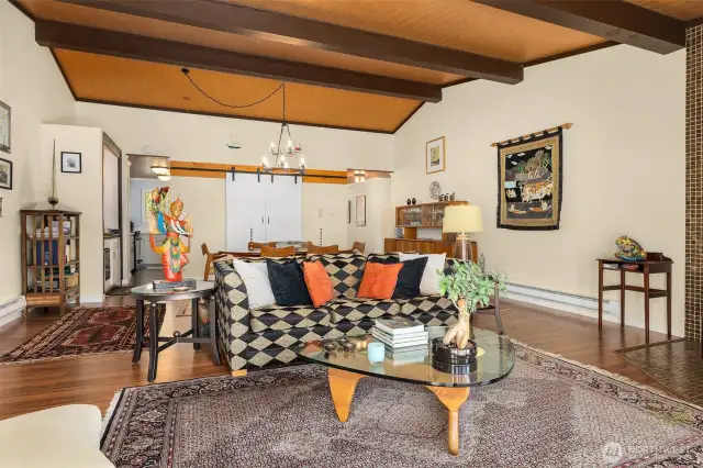 Functional layout highlights the open flow between the dining and living rooms, enhanced by vaulted pine plank ceilings.