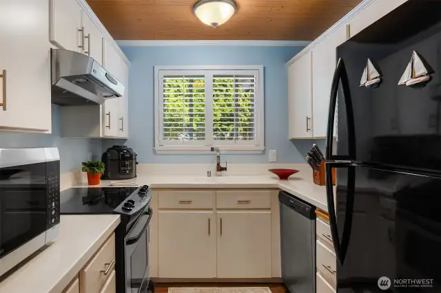Kitchen with large window with view across to green tree line.