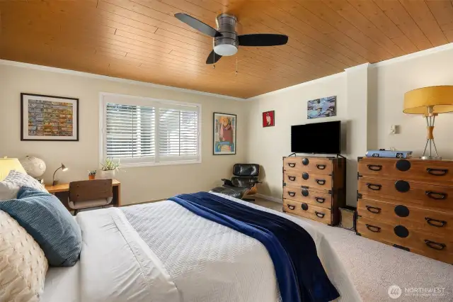 Bedroom space highlighting pine plank ceilings and window bringing in natural light.