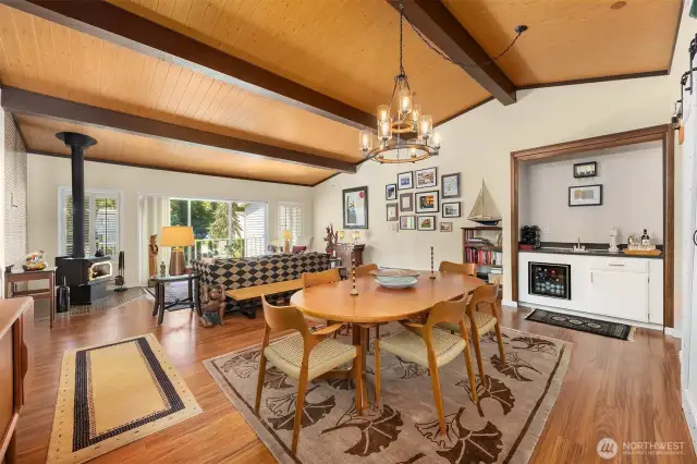 Open-concept dining and living areas offering a functional flow, complemented by vaulted pine plank ceilings and sunlit windows.