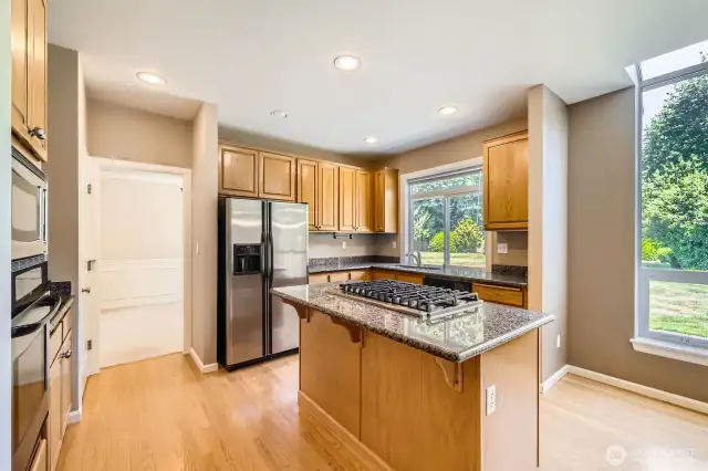 The spacious island kitchen features a newer Viking 6-burner gas range, newer dishwasher, stainless steel appliances and slab granite countertops.