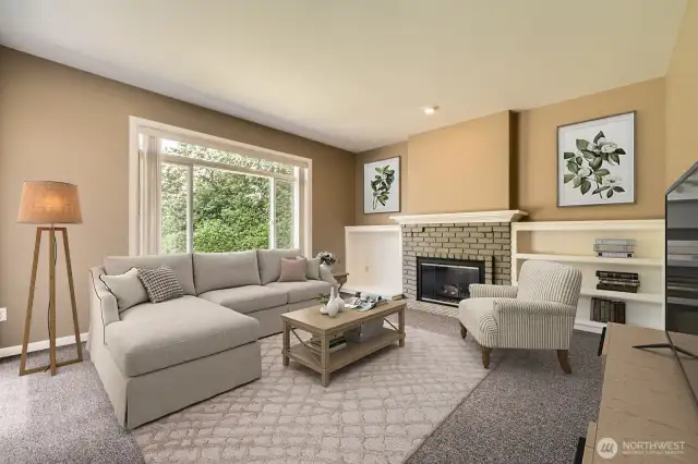 The family room is spacious with large windows bringing in plenty of natural light. It features built-in shelving, a brick gas fireplace, and more.
