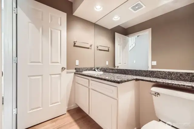 The powder room with slab granite countertops and hardwood floors.