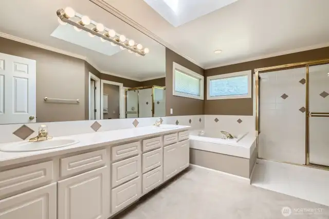 The spacious 5-piece primary bath features tile flooring, a soaking tub and large skylight.
