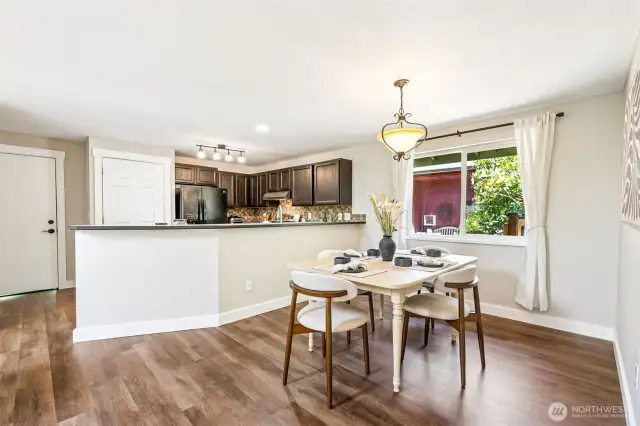 The open kitchen features a breakfast bar. Fresh updates throughout, including new trim and vinyl plank flooring.