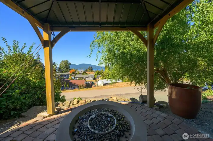 The backyard has low maintenance natural landscaping along with a firepit and covered gazebo.