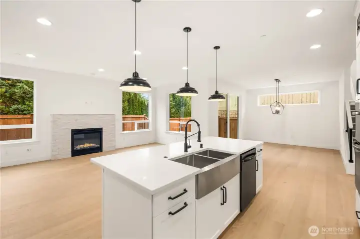 The great room offers generous natural light, a sleek gas fireplace framed by stone surround, and views of the fenced backyard. The open-concept layout connects seamlessly to the kitchen and dining areas, creating a flexible and inviting space for gatherings or quiet evenings. Wide-plank flooring enhances the bright, modern feel throughout.    These photos are from lot 3 at Gooden Hollow, the actual home for sale. However, other homes may vary, so all photos, renderings, site maps, and floorplans are for visualization purposes only. Plans, colors, building orientation, finishes, home outlook, and other details can and WILL vary.