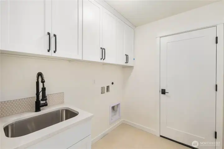 The upper-level laundry room includes generous cabinetry, a deep utility sink, and thoughtful storage to keep daily tasks running smoothly. Its placement near the bedrooms adds convenience and efficiency.    These photos are from lot 3 at Gooden Hollow, the actual home for sale. However, other homes may vary, so all photos, renderings, site maps, and floorplans are for visualization purposes only. Plans, colors, building orientation, finishes, home outlook, and other details can and WILL vary.