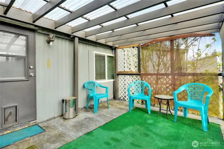 The covered  back porch looking North. There are plants and trees that provide shade and privacy during the summer.
