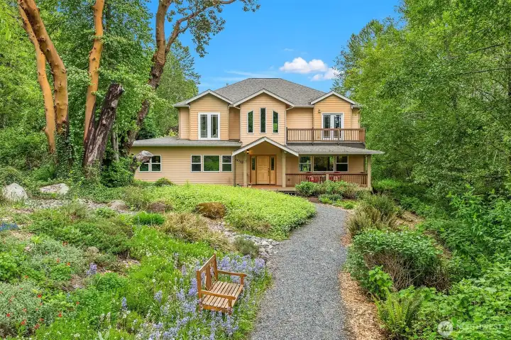 Quaint pathway leads to gorgeous home on lush, shy acre lot.
