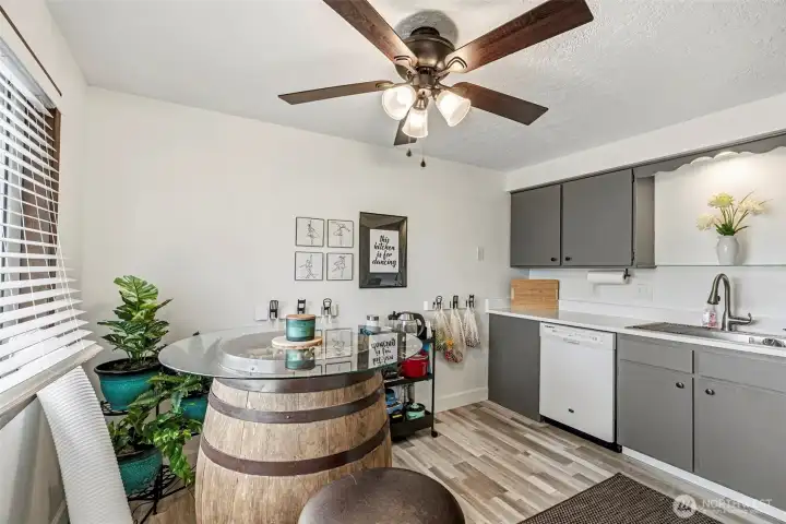 Modernized kitchen featuring new flooring, cabinets, quartz countertops, appliances, light fixtures, and fresh paint. View from the entryway.