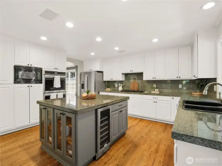 Whether preparing a quiet breakfast or hosting friends, this expansive kitchen is designed to bring people together. Featuring generous granite work surfaces, abundant storage, stainless steel appliances, a large center island with beverage fridge, and warm hardwood floors, every detail supports effortless daily living. Whether preparing a quiet breakfast or hosting friends, this expansive kitchen is designed to bring people together. Featuring generous granite work surfaces, abundant storage, stainless steel appliances, a large center island with beverage fridge, and warm hardwood floors, every detail supports effortless daily living.