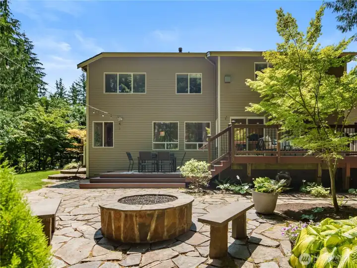 Your own outdoor retreat awaits. A spacious deck overlooks a stunning flagstone patio anchored by a built-in fire pit, while lush landscaping and mature trees create a picturesque backdrop for everything from summer barbecues to cozy evenings under the stars. Your own outdoor retreat awaits. A spacious deck overlooks a stunning flagstone patio anchored by a built-in fire pit, while lush landscaping and mature trees create a picturesque backdrop for everything from summer barbecues to cozy evenings under the stars.