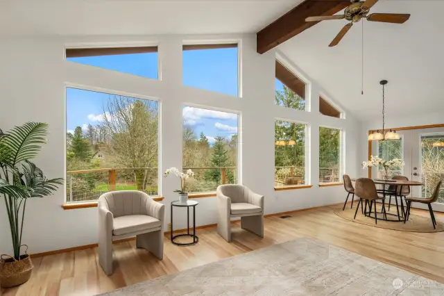 The living room gently flows into the dining area. French doors in the background lead to the upper deck as well as a stairway down to the lower patio area.