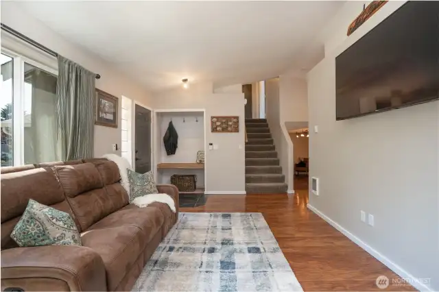 Living room looking to carpeted stairs that lead to the upper level, and beyond you will notice the lower level family room. Note the tile floor entry and the darling nook with a large shelf & shiplap surround.