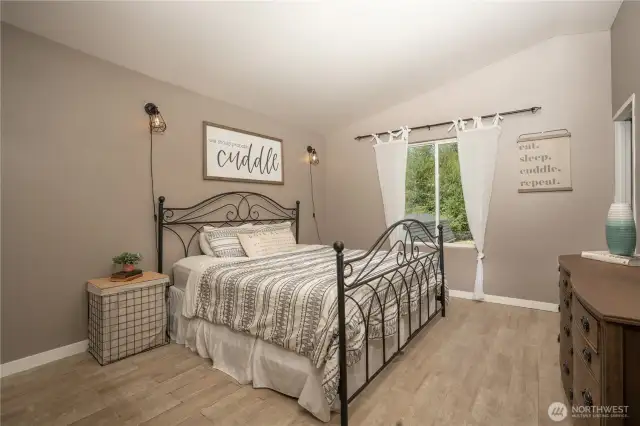 Facing the private & expansive back yard the primary bedroom with tile plank flooring & refreshed paint make for a calming retreat.