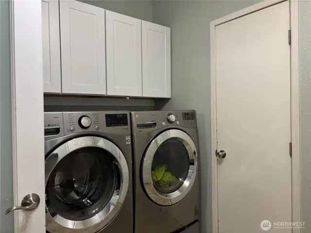 closer look at the washer and dryer as they stay with the home, plus cabinets above for storage.