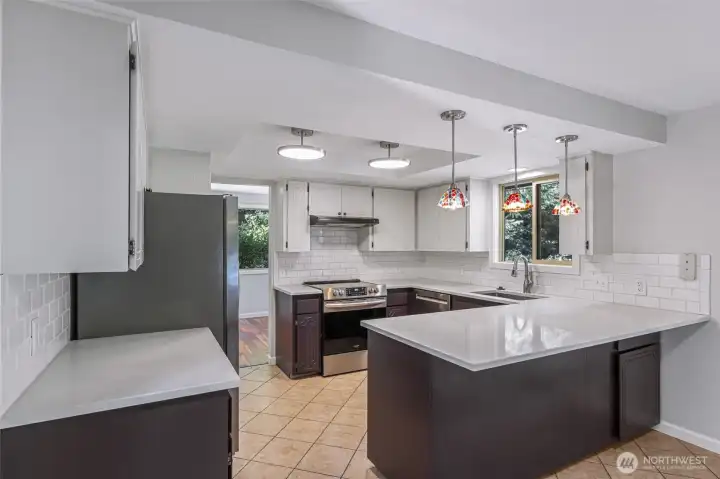 Kitchen with eating bar, new lighting, counters,sink and tiled floors