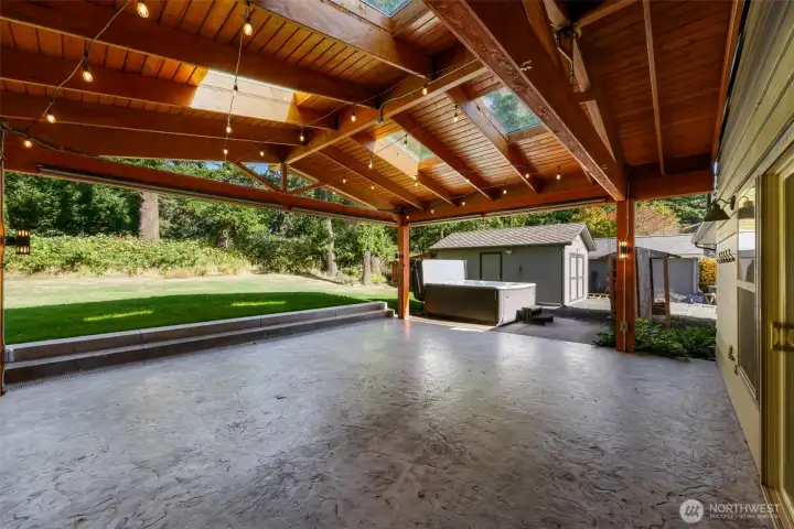 GRAND chalet style covered patio with stained concrete, skylights and powered lights and plugs next to the large hot tub