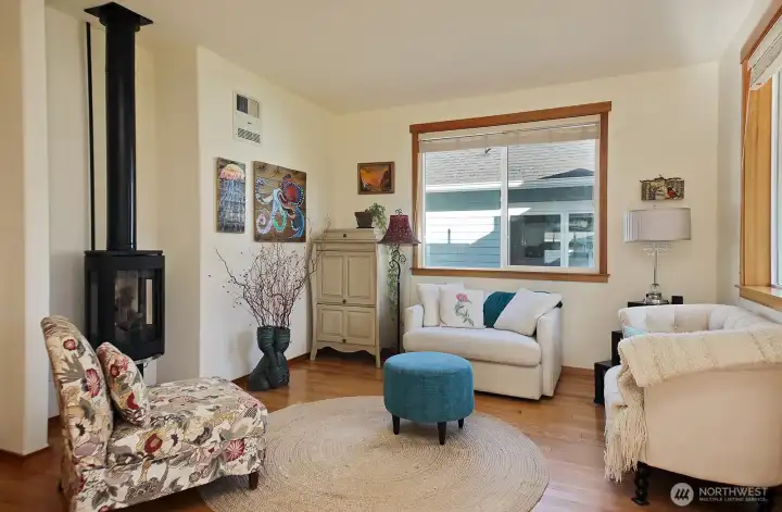 Cozy living room with fireplace, fantastic window package for light (sellers have installed shades for privacy) and pretty hardwood flooring in the great room space and hall leading to Primary Suite, Office and Half Bath.