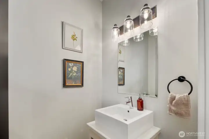 Main-level powder room featuring modern lighting, clean lines, and a sleek vanity design. A convenient guest bathroom located on the main floor for everyday living and entertaining.