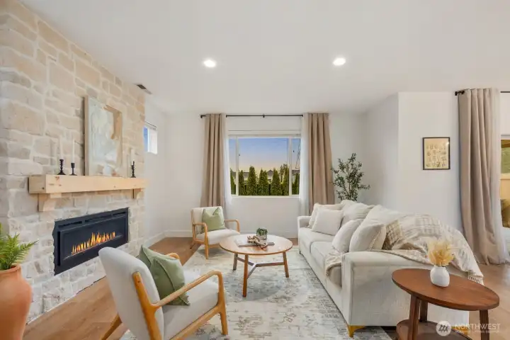Bright and inviting living room anchored by a dramatic floor-to-ceiling stone fireplace and large picture window overlooking the backyard. This open living space is designed for comfort, natural light, and effortless gathering.