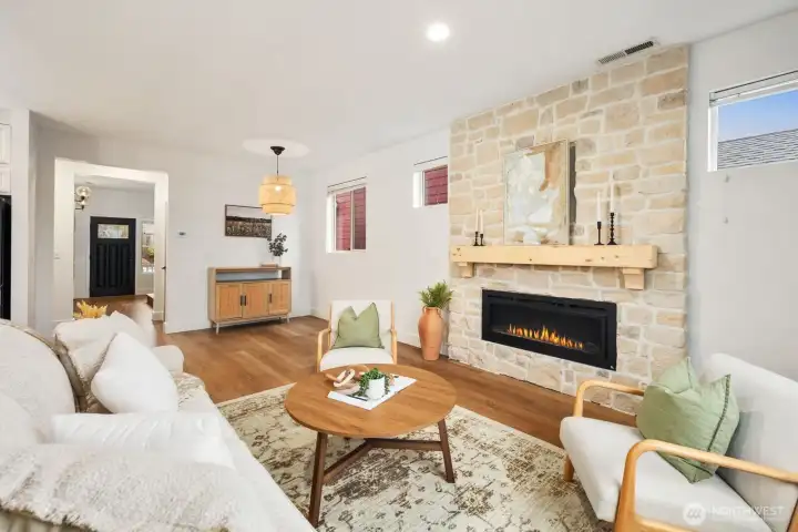 From this angle, the living room flows seamlessly toward the entry and main hallway, highlighting the open layout and natural connection between living spaces. The fireplace wall creates a warm focal point while the surrounding space feels bright and welcoming.