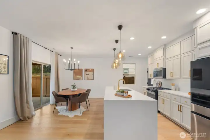 Spacious kitchen with large center island, pendant lighting, and abundant cabinetry storage overlooking the dining area. The open design keeps everyone connected whether cooking, dining, or entertaining.