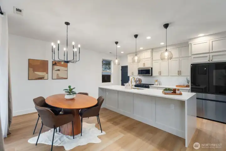 Bright entertainer’s kitchen featuring a large island with seating, modern lighting, and extensive cabinetry extending along the wall for added storage and functionality. The layout is designed for both daily living and gathering with friends and family.